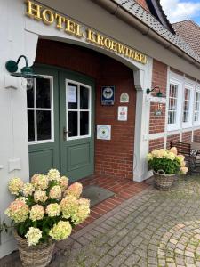 ヒットフェルトにあるHotel Krohwinkelの緑のドアと花が正面に飾られた建物