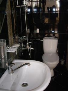 a bathroom with a white sink and a toilet at Family Hotel Avramov in Vidin