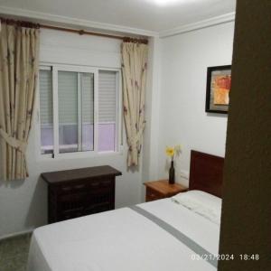una camera da letto con un letto bianco e una finestra di Stephen a Torrevieja