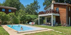 a family in a swimming pool in front of a house at Résidence Château de Salles in Salles