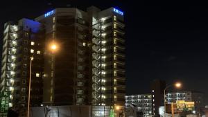 Toyoko Inn Nishi Funabashi Baraki Inter في إيشيكاوا: مبنى طويل وبه أضواء زرقاء في الليل