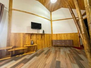 a room with a tv and a wooden floor at Long Cốc Ecolodge  +3 photos