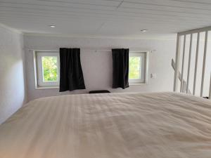 a bedroom with a large bed and two windows at PaprikanTiny House in Uppsala