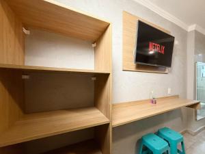 a room with wooden shelves and a tv on the wall at Marmeu Tombo com Hidro Aquecida Privativa in Guarujá