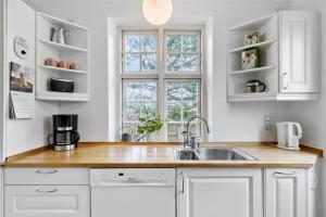 a kitchen with white cabinets and a sink and a window at 1278-N-Liseleje-Kystvej-12 in Liseleje