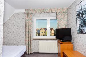 a bedroom with a tv and a window at Hotel Victory Home - 10min Lotnisko Chopina, 15min to Zachodni, 5min to Progresja in Warsaw