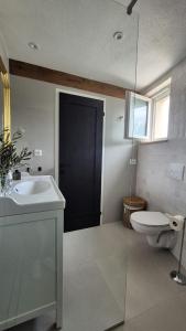a bathroom with a toilet and a sink and a black door at For a couple - beautiful sea view in Postira +20 photos