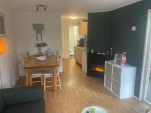 a kitchen and living room with a table and a fireplace at Chalet in de bossen bij Garderen in Putten