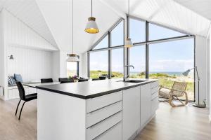 a white kitchen with a black counter top and some chairs at LK1240-Lokken-Rosavej-13 in Løkken