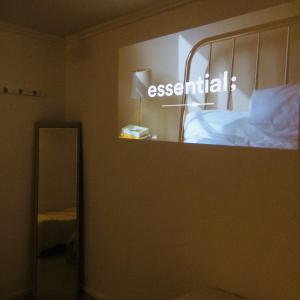 a mirror in a room with a bed and a sign that says essential at Cozy Butter Stay Jeonju in Jeonju