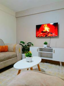 a living room with a couch and a tv on a wall at Cosy Homes Eldoret in Eldoret