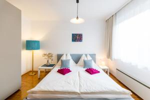a bedroom with a large white bed with pink pillows at Appartmenthaus Josefikeller in Podersdorf am See