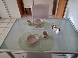 a glass table with two plates and cups on it at Hofmann's Ferienwohnung in Bad Neuenahr-Ahrweiler