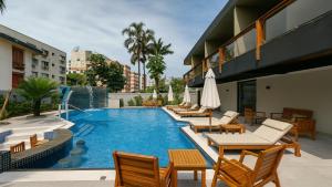 una piscina con sillas y mesas y un hotel en Marmeu Tropical (Com garagem), en Guarujá