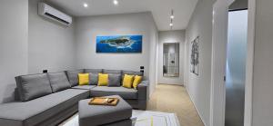 - un salon avec un canapé gris et des oreillers jaunes dans l'établissement City Center Rooms Durres, à Durrës