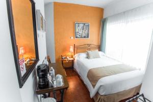 Dormitorio pequeño con cama y espejo en Hotel Pórtico Cultural, en Morelia