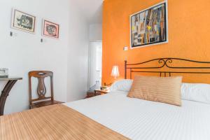 a bedroom with a bed with an orange wall at Hotel Pórtico Cultural in Morelia