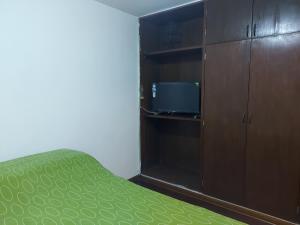 リマにあるKUSIHausのベッドルーム1室(ベッド1台付)、キャビネット(テレビ付)