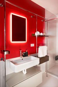 a bathroom with a white sink and a red wall at NEST LIVING - Red Velvet in Udine +9 photos