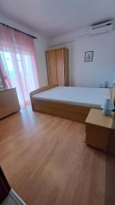 a large bed in a room with a wooden floor at Apartmani Azik in Lopar