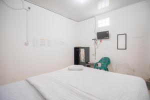 a bedroom with a white bed and a green chair at Urbanview Hotel Mine Residence Syariah in Padang