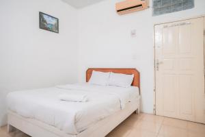 a bedroom with a white bed and a white door at Urbanview Hotel Mine Residence Syariah in Padang