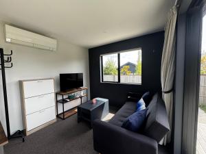 Queenstown AirportにあるMeraki Guesthouseのソファと窓のあるリビングルーム
