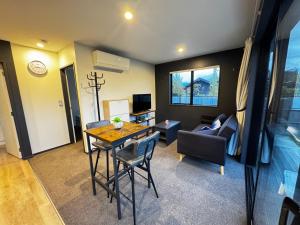 Queenstown AirportにあるMeraki Guesthouseのテーブルと椅子とソファのあるリビングルーム