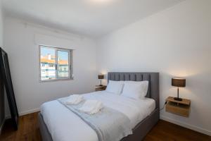 ein Schlafzimmer mit einem großen weißen Bett mit einem Fenster in der Unterkunft Carcavelos Blue Sea II in Carcavelos