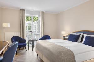 a bedroom with a large bed and blue chairs at Dorint Parkhotel Meißen in Meißen