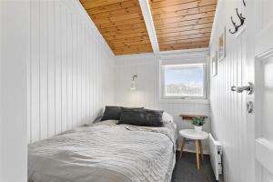 a bed in a white room with a wooden ceiling at LK1247-Lokken-Falkevej-3 in Løkken