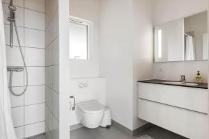 a white bathroom with a toilet and a sink at LK1463-Lokken-Rosavej-11 in Løkken +16 photos