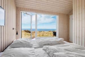 a bedroom with a bed and a large window at LK1463-Lokken-Rosavej-11 in Løkken