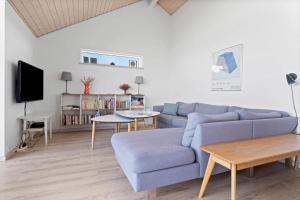 a living room with a blue couch and a tv at LK1463-Lokken-Rosavej-11 in Løkken