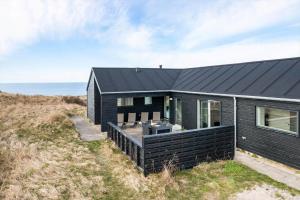 a black house on a hill with the ocean in the background at LK1463-Lokken-Rosavej-11 in Løkken