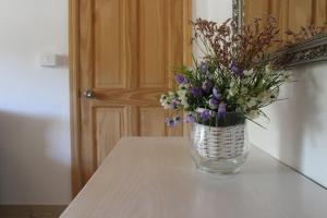 Un jarrón lleno de flores sobre una mesa. en Dimora Sogni di campagna, en Teulada
