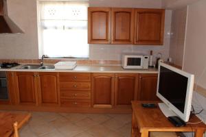 Una cocina con gabinetes de madera y un monitor de computadora sobre una mesa. en Dimora Sogni di campagna, en Teulada