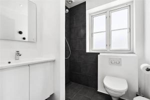 a white bathroom with a toilet and a window at LK1294-Lokken-Josefines-Have-123 in Løkken +18 photos