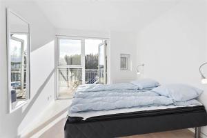 a bed in a white room with two windows at LK1106-Lokken-Strandparken-32 in Løkken