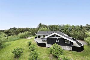 a black house with a deck in a field at LK626-Lokken-Magdalenevej-40 in Løkken