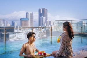 a man and a woman sitting in a swimming pool at San Marino Boutique Danang - 10 mins to Dragon Bridge & 15 mins to My Khe Beach in Da Nang