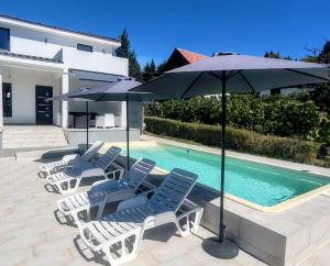a group of chairs and umbrellas next to a pool at Villa Kally Fruska Gora in Velika Remeta