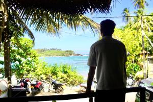 a man standing on a balcony looking out at the ocean at The Cabana Hotel Hiriketiya in Dickwella