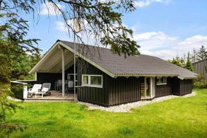 a black cottage with a deck and two chairs at LK599-Lokken-Stellavej-16 in Løkken