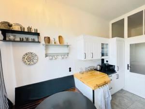 a kitchen with white cabinets and a wooden table at Palais Ewald in Herzogenburg