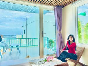 a woman sitting in a chair on a balcony at Villa Đại Dương View Biển Đảo Phú Quý in Cu Lao Thu