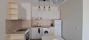 Una cocina con gabinetes blancos, fregadero y lavavajillas. en Lighthouse GbA 304, en Balchik