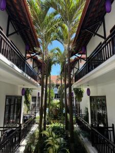 a courtyard with palm trees in front of a building at TTC Hotel - Hoi An in Hoi An