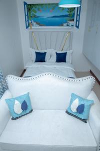 a white bed with two blue pillows on it at Lush Air Bnbs in Karen in Nairobi +7 photos