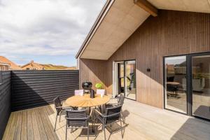 a patio with a wooden table and chairs on a deck at 244-Harboore-Knaresbrovej-17 in Harboør